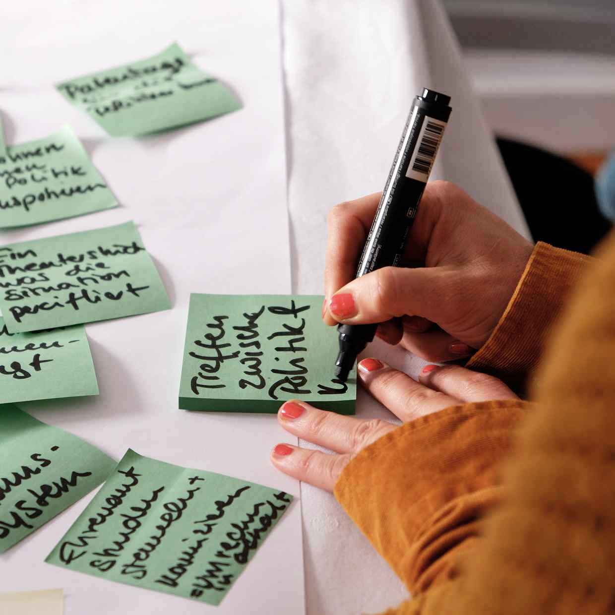 Großaufnahme einer Hand, die ein Post-it beschreibt
